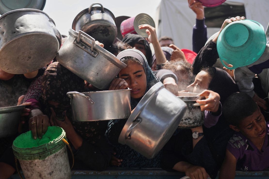 Palestinians struggle to get donated food at a community kitchen in Khan Younis, Gaza Strip on Monday.