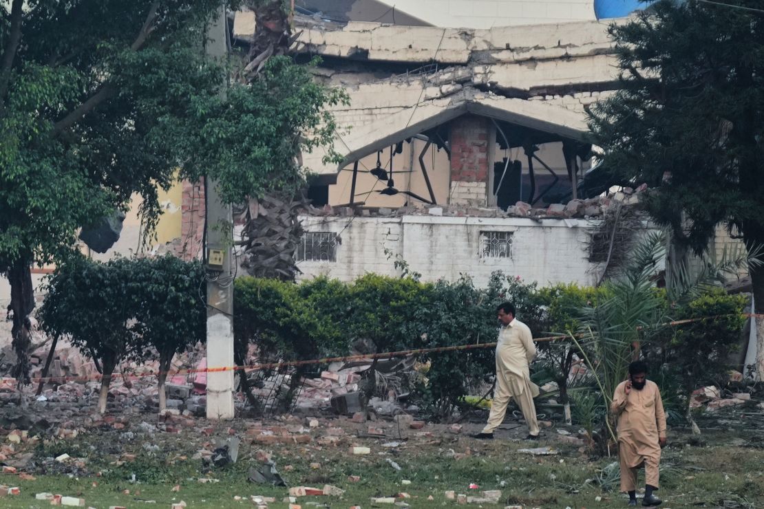 Local residents walk through rubble of a building damaged by an Indian missile strike, in Muridke, Pakistan, on Wednesday