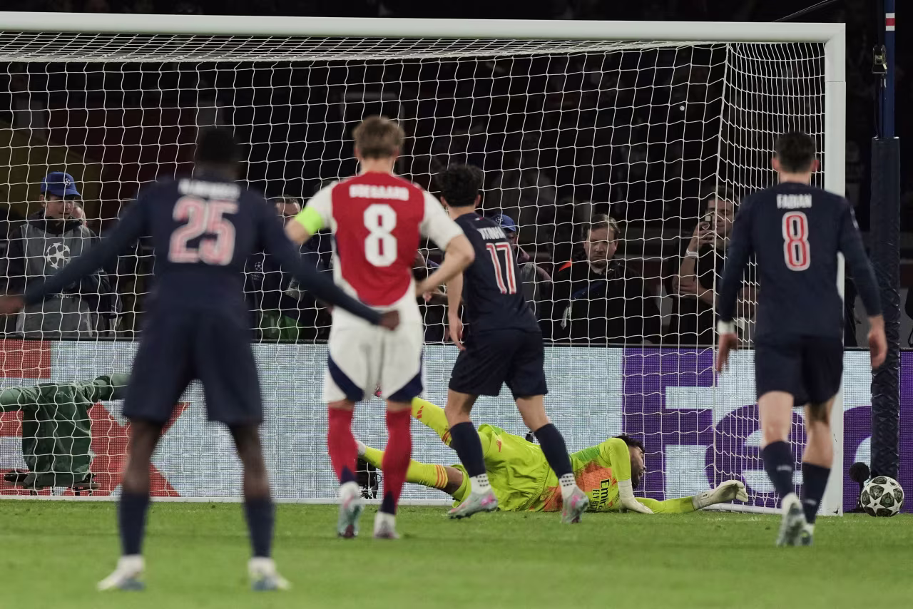 Arsenal goalkeeper David Raya saves a penalty by Paris Saint-Germain's Vitinha.