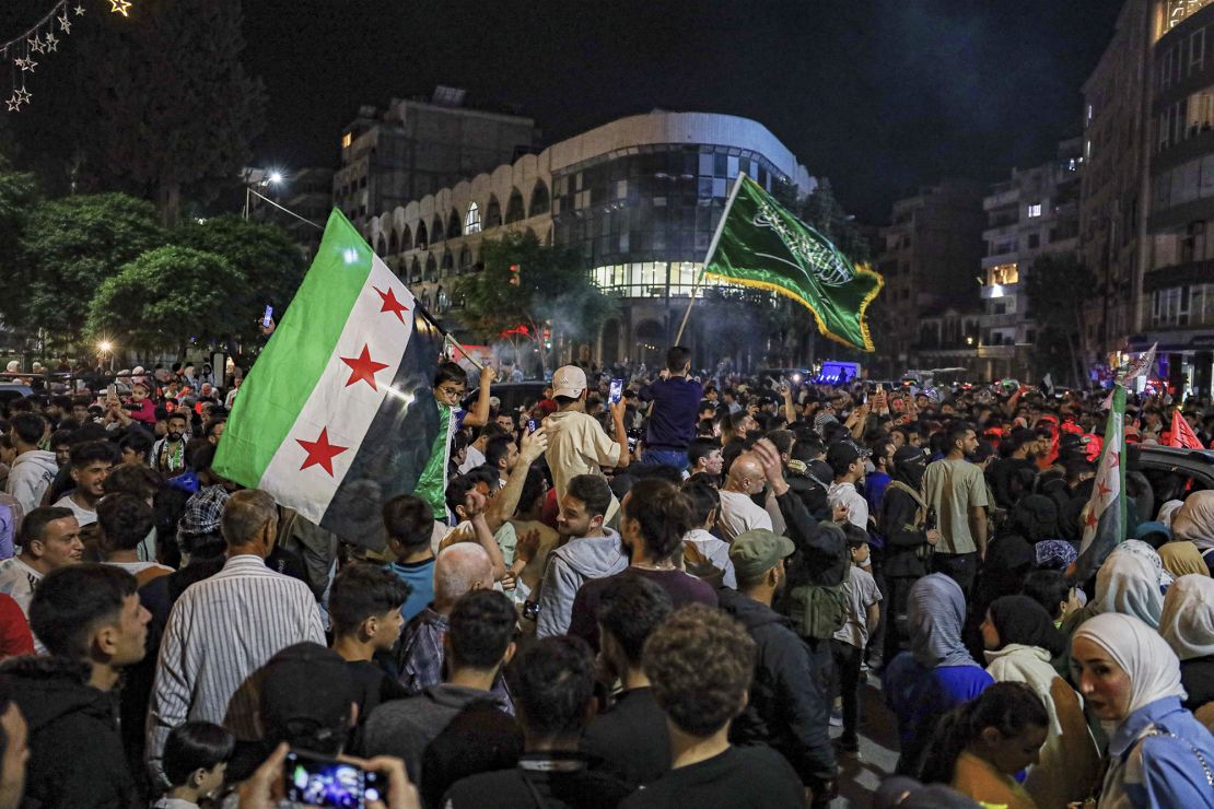 Syrians wave Saudi and Syrian flags in celebration after U.S. President Donald Trump announced plans during his visit to Saudi Arabia to ease sanctions on Syria and normalize relations with its new government, in Homs, Syria, late Tuesday, May 13, 2025.(AP Photo/Omar Albam)