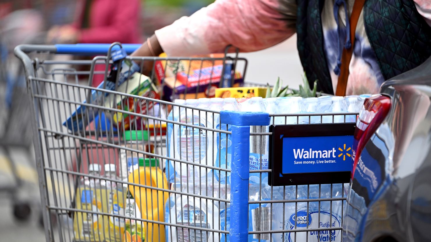 A consumer loads items from shopping cart into their car at a Walmart Supercenter retail store.