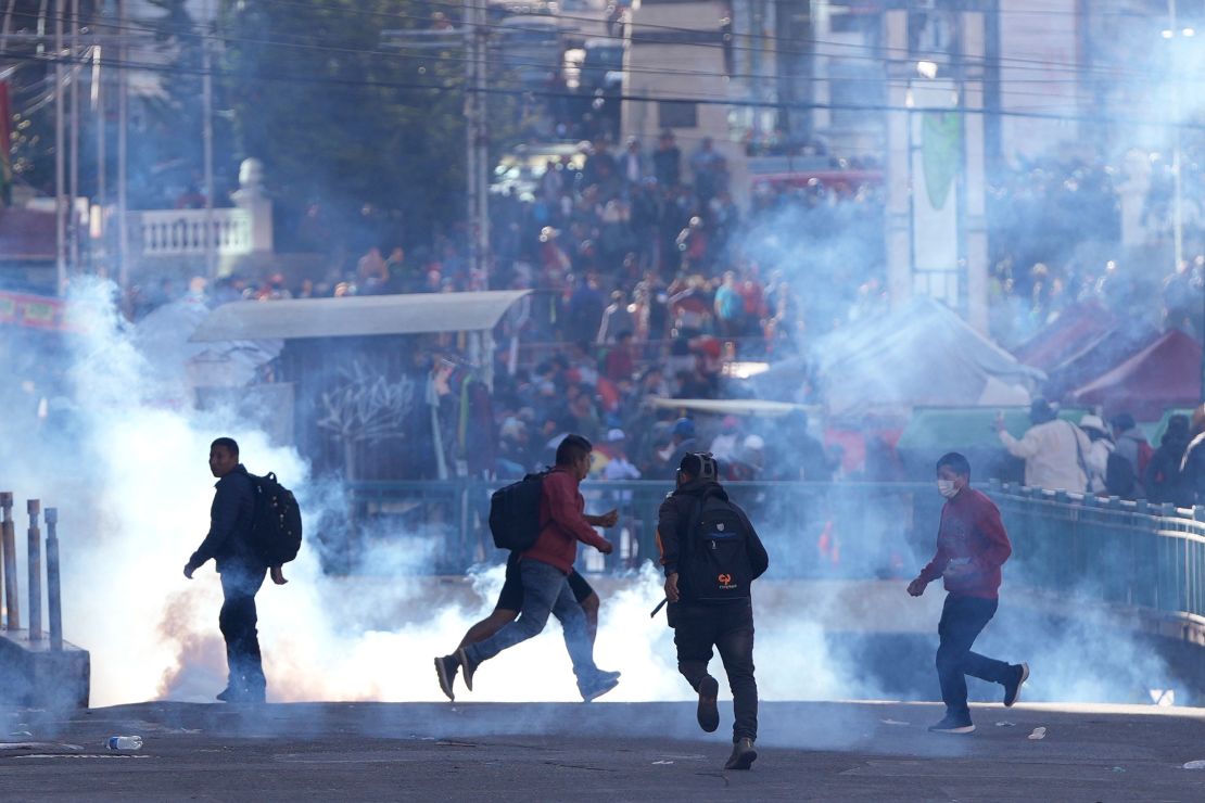 Supporters of former President Evo Morales run from tear gas launched by police.
