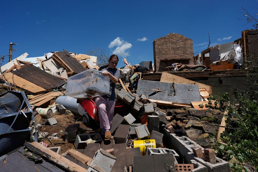 Grier Allen carries Lynn White's pet turtle in a plastic bin from what is left of White's home, Saturday, May 17, 2025, in London, Ky. (AP Photo/Carolyn Kaster)