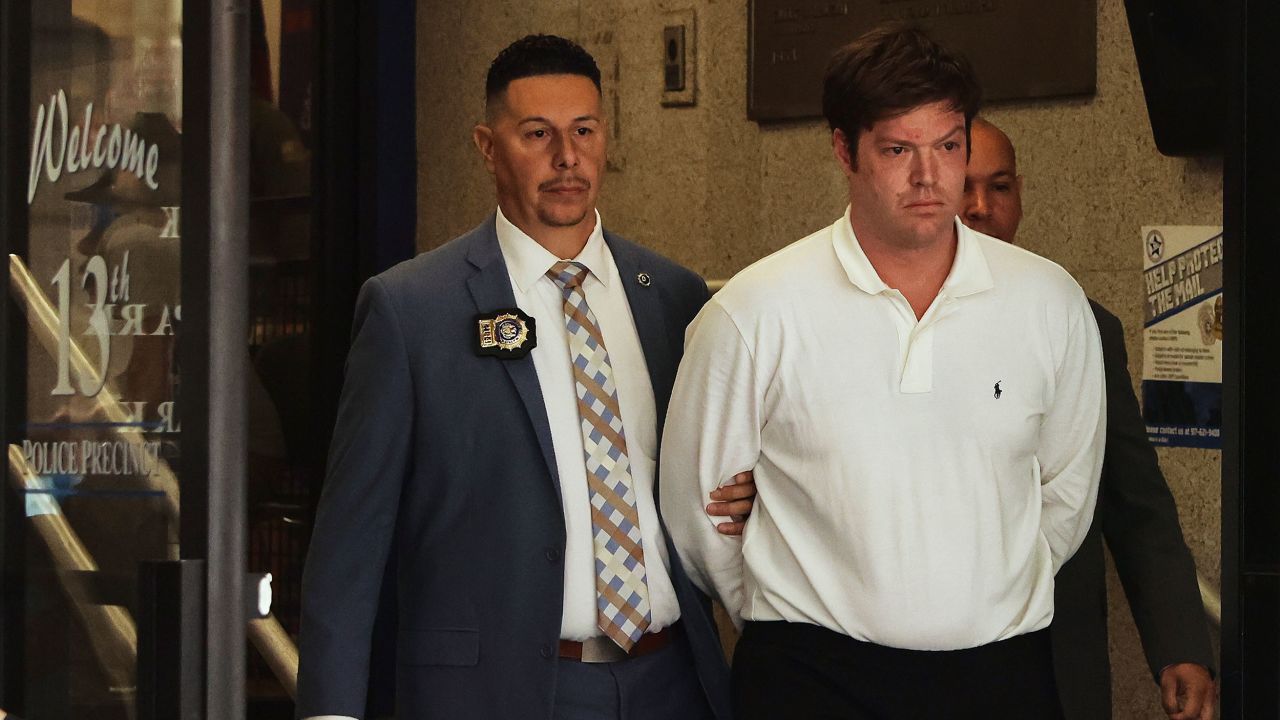 William Duplessie, right, is escorted out of the New York Police 13th Precinct after turning himself in on charges of kidnapping and false imprisonment, Tuesday, May 27, 2025, in New York.