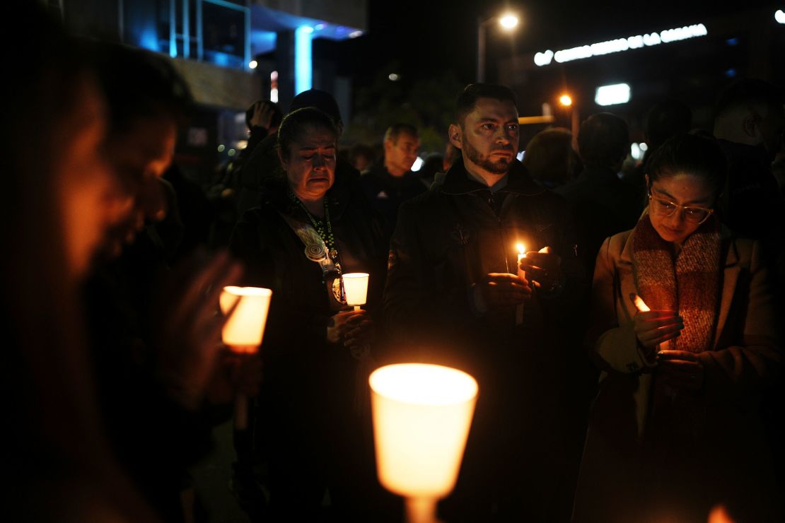 People hold candles during a vigil outside the Santa Fe hospital where Miguel Uribe is being treated.