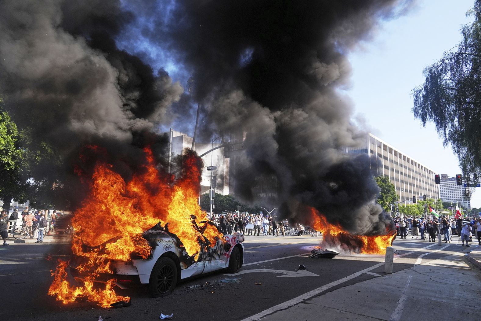Two Waymo taxis burn near the Metropolitan Detention Center on Sunday.