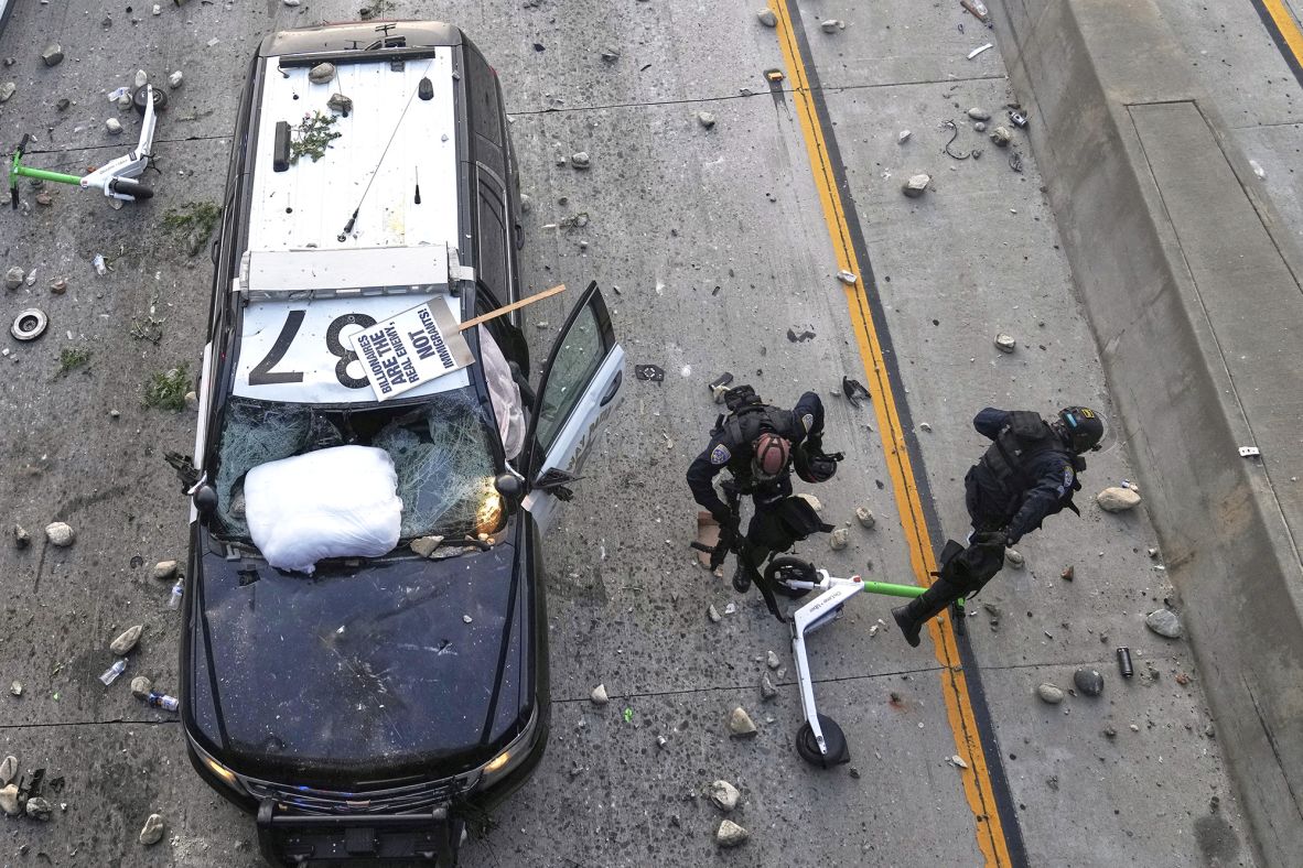 Two California Highway Patrol officers try to dodge rocks being thrown near the Metropolitan Detention Center on Sunday.
