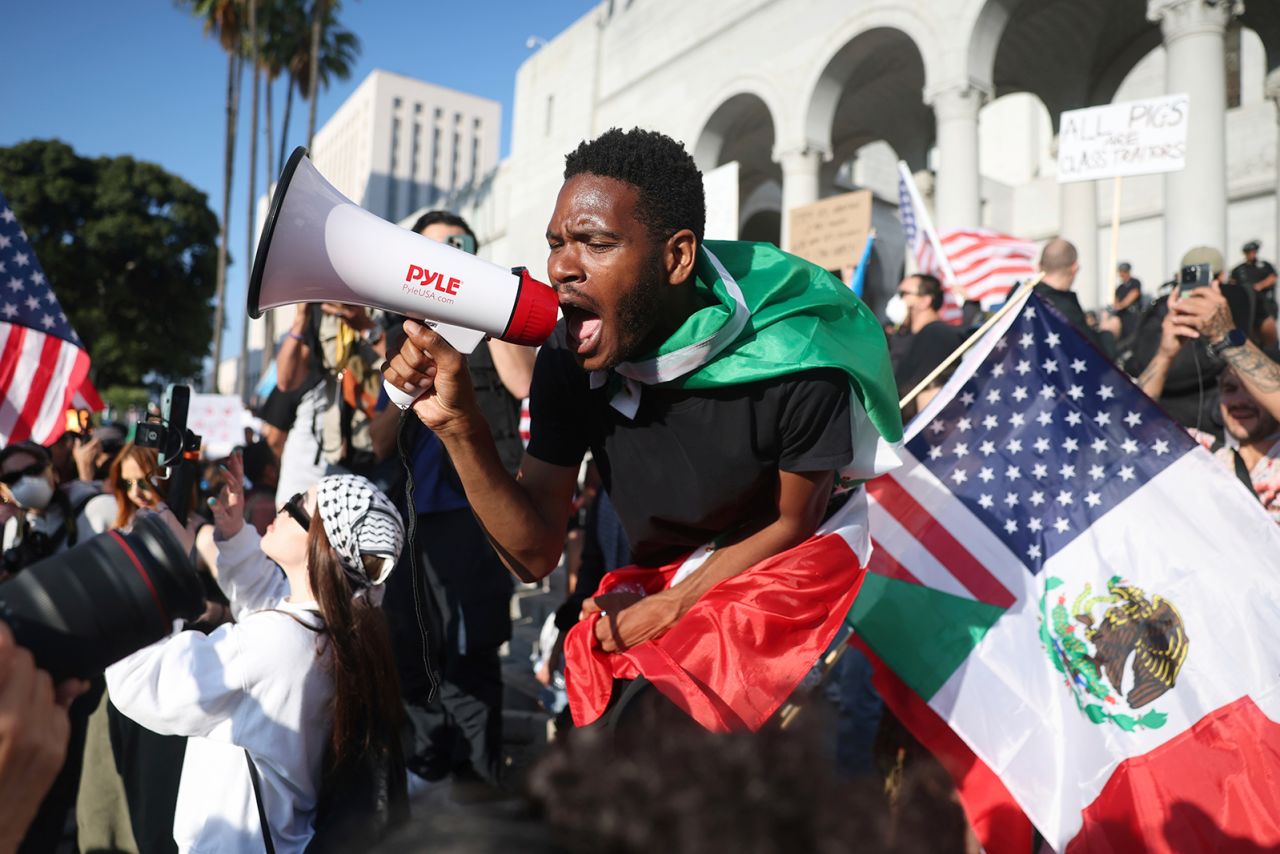 A man shouts into a megaphone outside City Hall during a protest in Los Angeles on Wednesday.