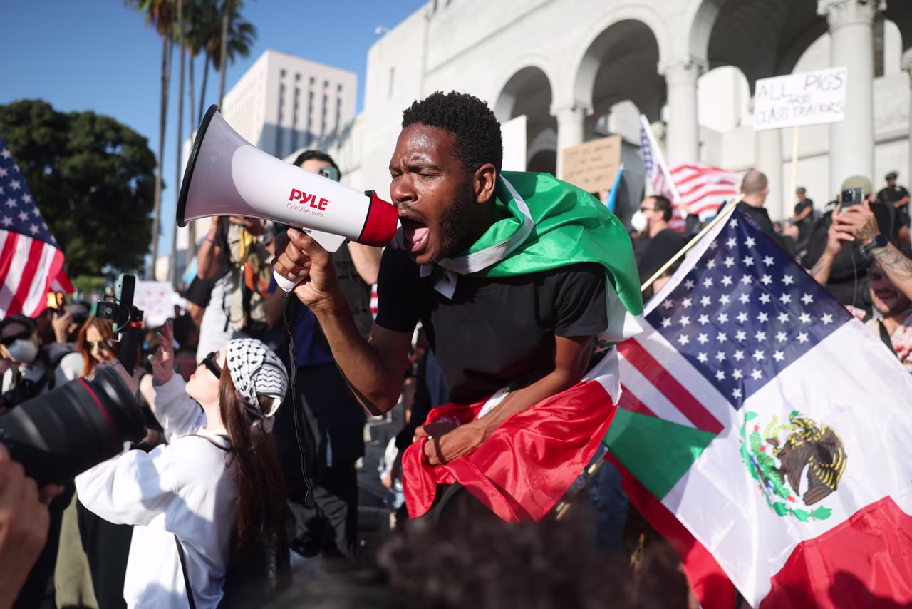 A man shouts into a megaphone outside City Hall during a protest in Los Angeles on Wednesday.
