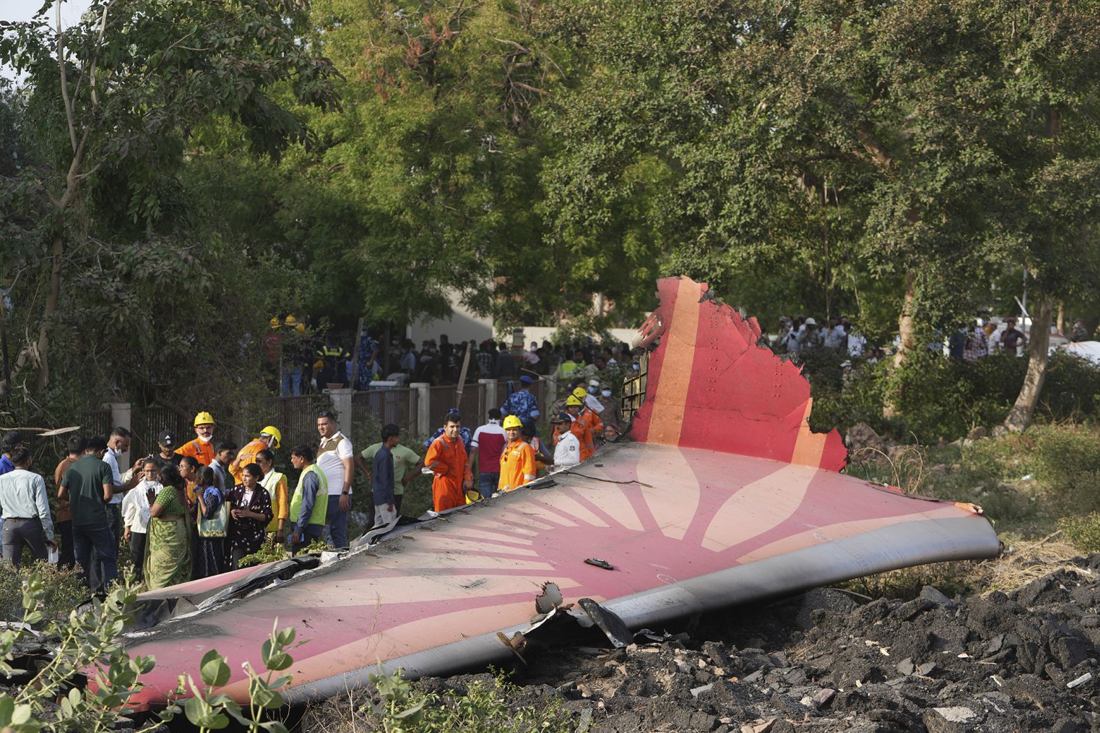 People stand around the debris of the airplane.