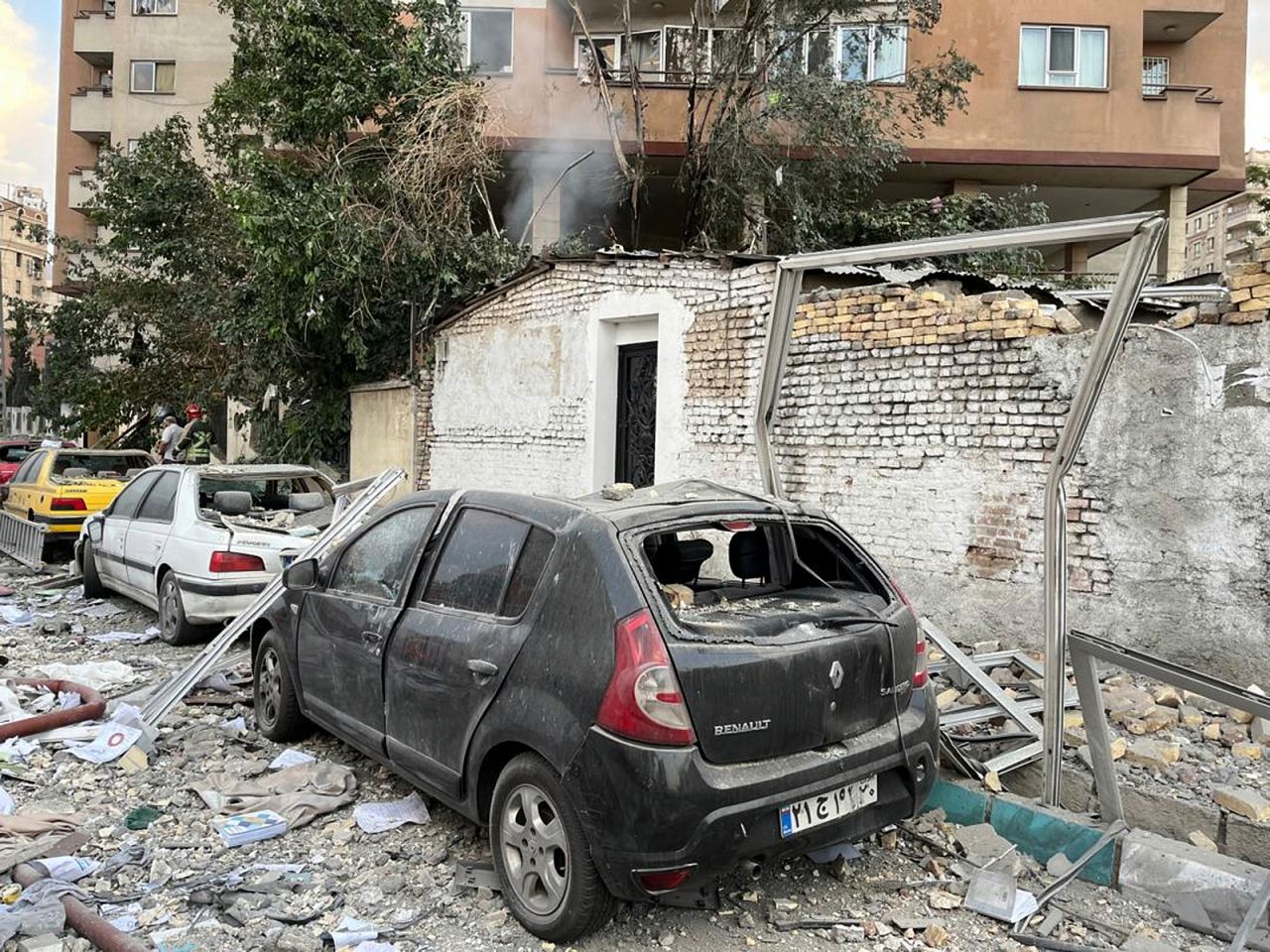 İran'ın başkenti Tahran'da cuma günü sabah saatlerinde gerçekleşen saldırının ardından bir apartman binasının enkazı park halindeki araçların üzerinde görülüyor.