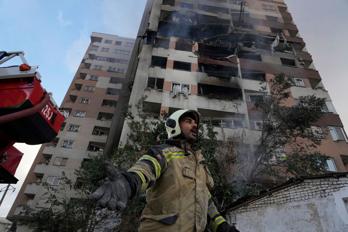 A firefighter calls out his colleagues at the scene of an explosion in a residential compound in northern Tehran, Iran, on June 13, 2025.