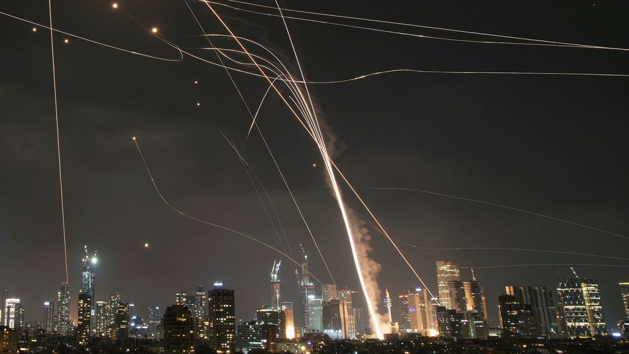 A projectile hits buildings as the Israeli Iron Dome air defense system fires to intercept missiles over Tel Aviv, Israel, on Friday, June 13.