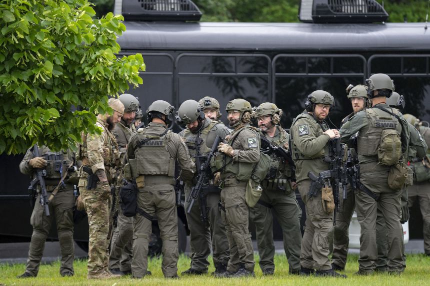 Law enforcement officers including local police, sheriff's deputies and the FBI stage near the scene of a shooting in Brooklyn Park, Minnesota on Saturday.