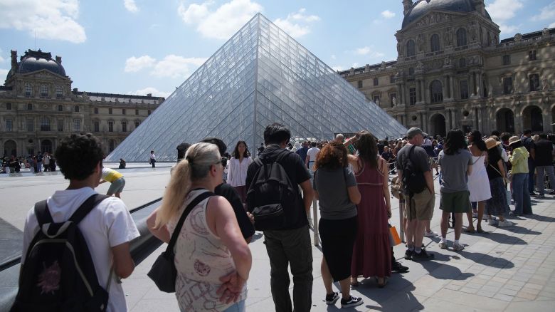 Tourists wait in line outside the Louvre museum which failed to open on time Monday, June 16, 2025 in Paris. (AP Photo/Christophe Ena)