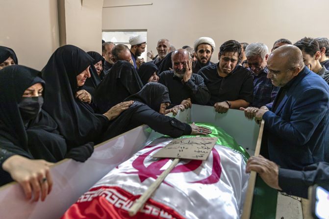 A mourner touches the shrouded body of a loved one who was killed in Israeli strikes in the Iranian city of Tabriz on Monday.