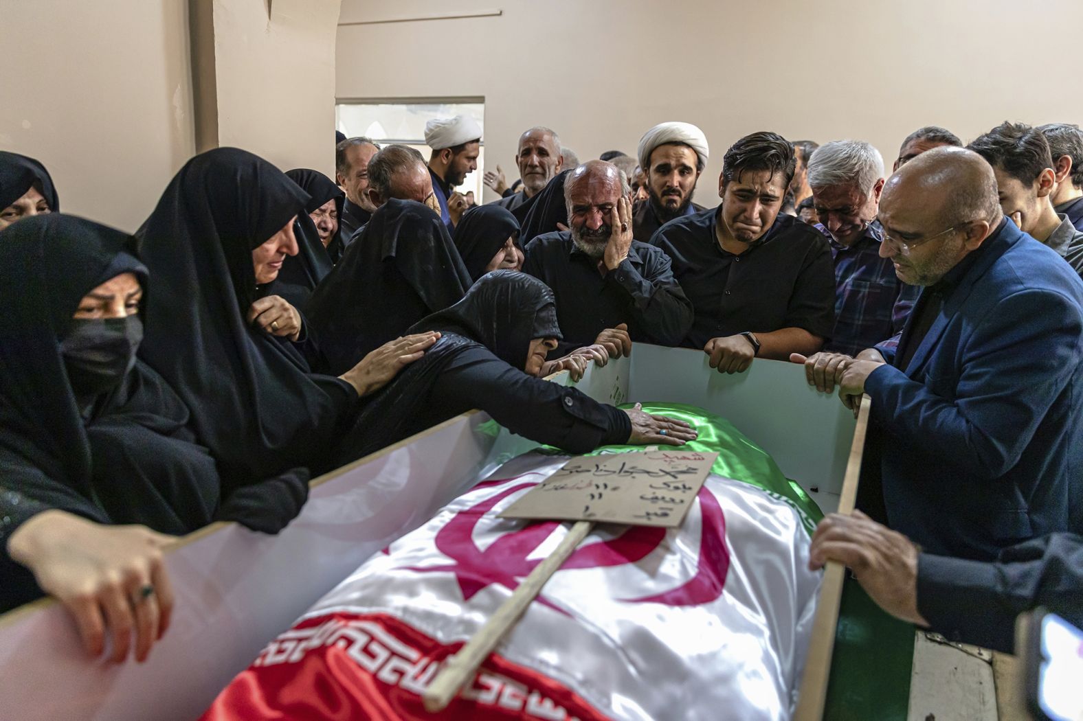 A mourner touches the shrouded body of a loved one killed in Israeli strikes in the Iranian city of Tabriz.