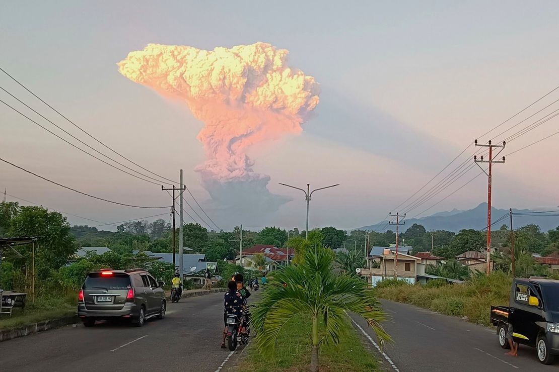 People watch as Mount Lewotobi Laki Laki spews volcanic materials into the air during the eruption on June 17, 2025.