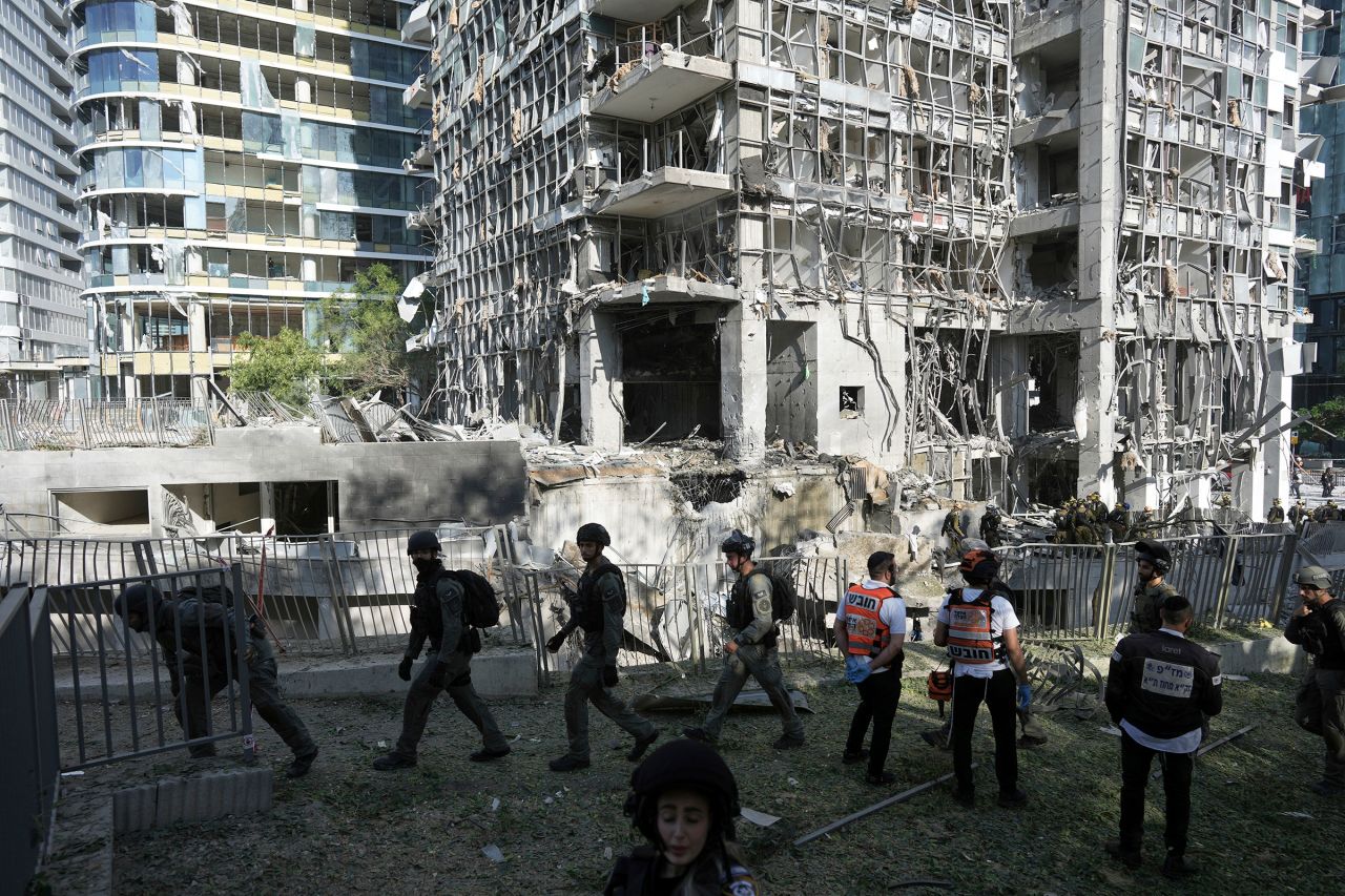 Kurtarma görevlileri ve askeri personel, Perşembe günü İsrail'in Ramat Gan kentinde İran'ın gerçekleştirdiği füze saldırısının yerini inceliyor.
