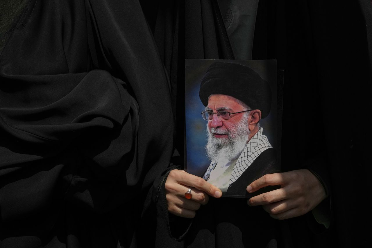 یک معترض پوستری از آیتالله علی خامنهای، رهبر عالی ایران را در جریان تظاهراتی برای محکومیت حملات اسرائیل به چندین شهر ایران، پس از نماز جمعه در تهران، در روز جمعه در دست دارد.