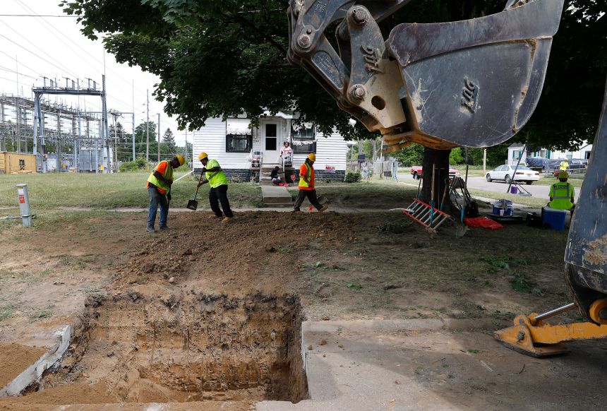 Workers backfill a hole used to replace a lead pipe with copper water supply lines to a home in Flint, Michigan, on July 20, 2018.