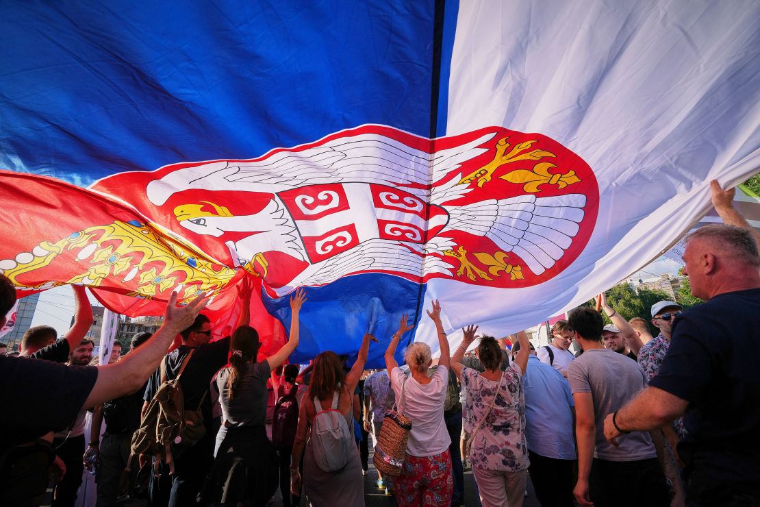 People walk under a large Serbian flag during a major anti-government rally in Belgrade on Saturday.