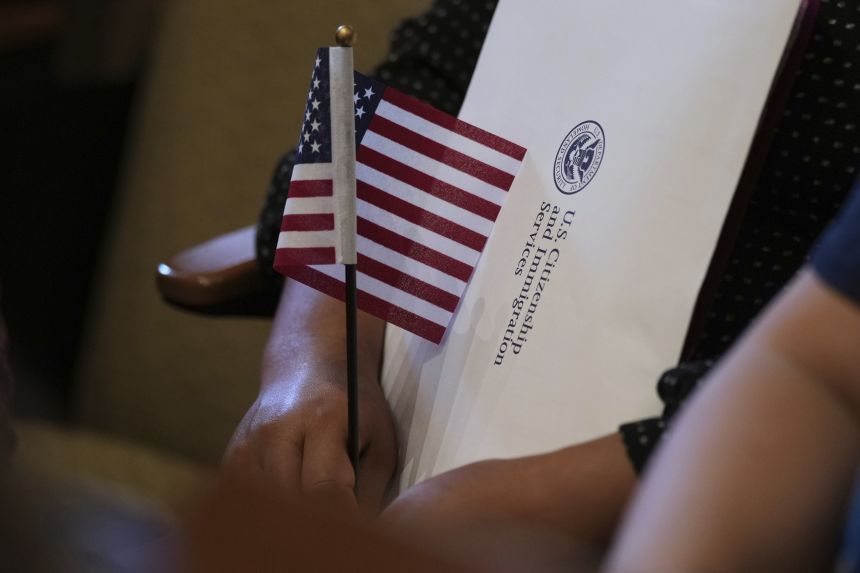 A woman clutches an American flag as she and applicants from 20 countries prepare to take the oath of citizenship during a naturalization ceremony in San Antonio, Texas, on July 3, 2025.