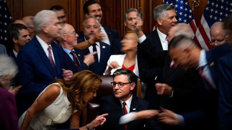 Republican members of Congress reach to shake hands with Speaker of the House Mike Johnson, R-La., center bottom, after Johnson signed President Donald Trump's signature bill of tax breaks and spending cuts, Thursday, July 3, 2025, at the Capitol in Washington. (AP Photo/Julia Demaree Nikhinson)