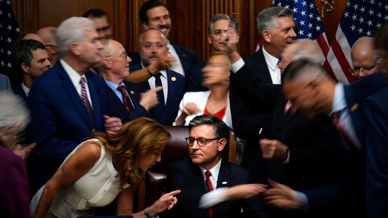 Republican members of Congress reach to shake hands with Speaker of the House Mike Johnson, R-La., center bottom, after Johnson signed President Donald Trump's signature bill of tax breaks and spending cuts, Thursday, July 3, 2025, at the Capitol in Washington. (AP Photo/Julia Demaree Nikhinson)