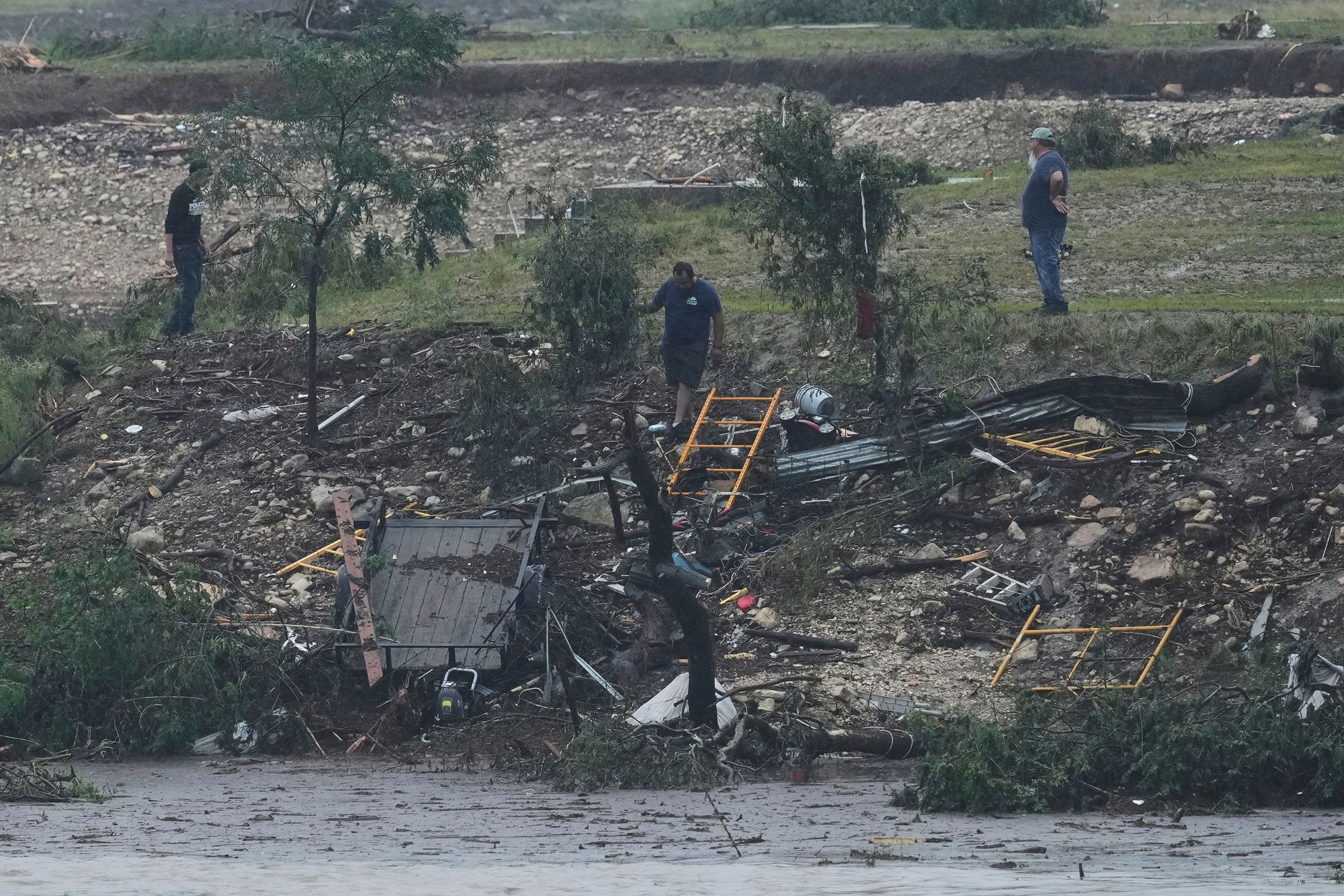 Men survey damage left by the flooded Guadalupe River in Kerrville.