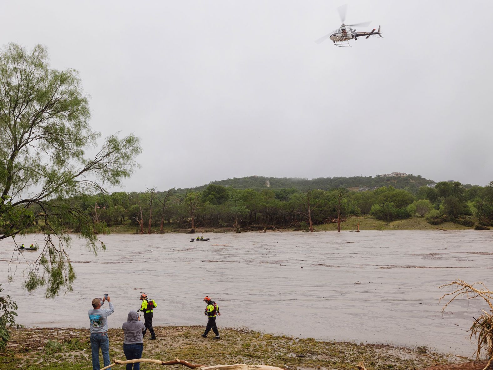 A Texas Department of Public Safety helicopter conducts an aerial search along the Guadalupe River in Kerrville, in the wake of destructive flooding on Friday.