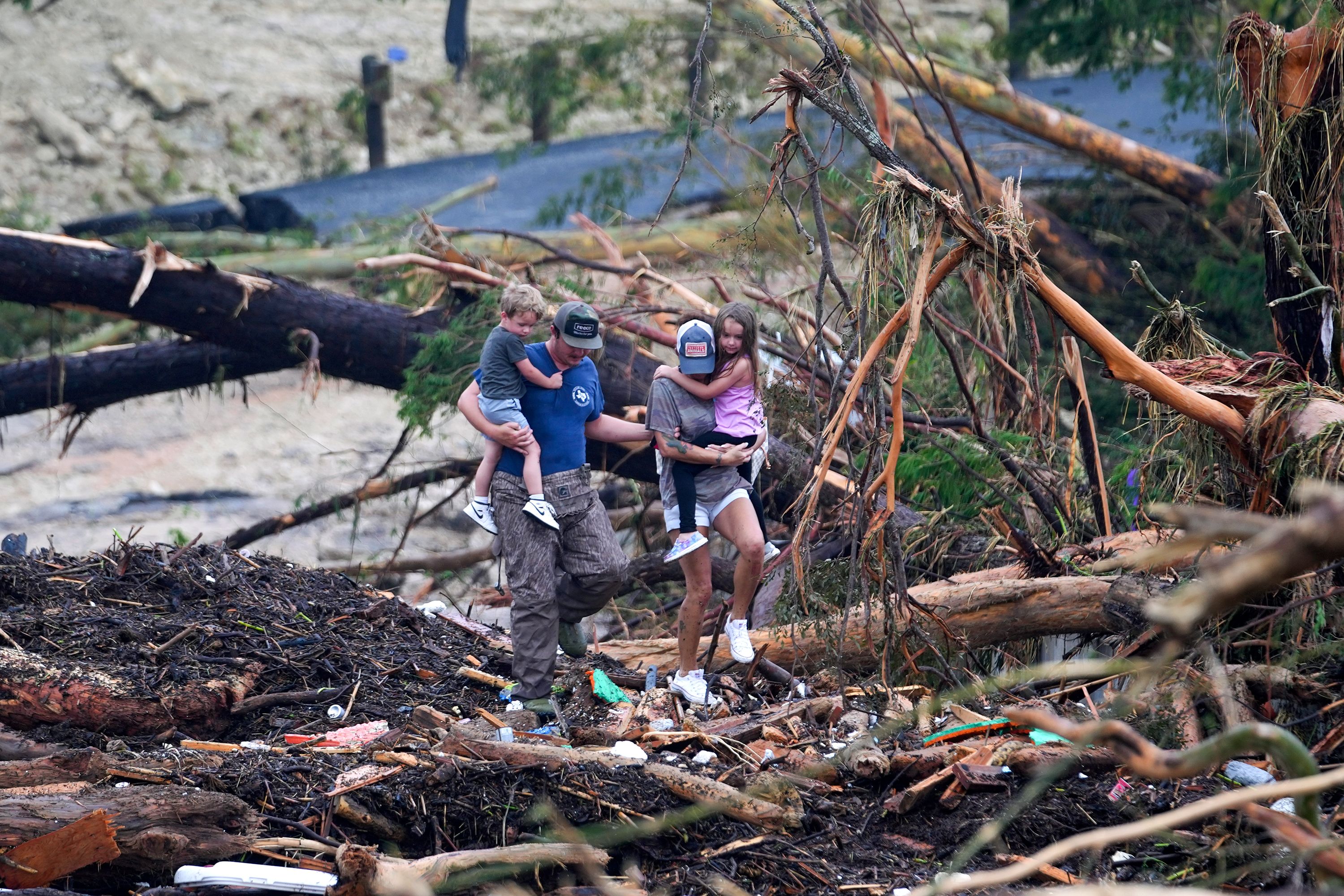 People climb over debris on a bridge atop the Guadalupe River in Ingram, Texas, on Saturday, July 5.