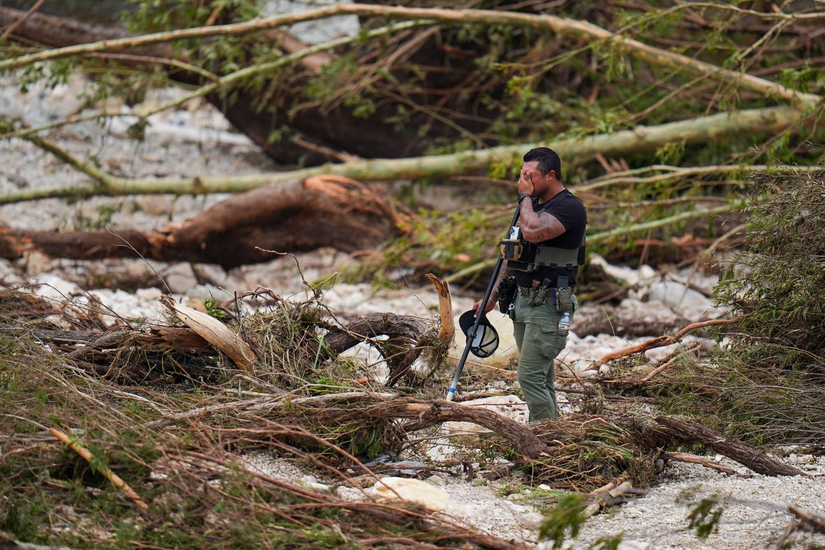 A sheriff's deputy pauses while combing through the banks of the Guadalupe River near Camp Mystic on Saturday.