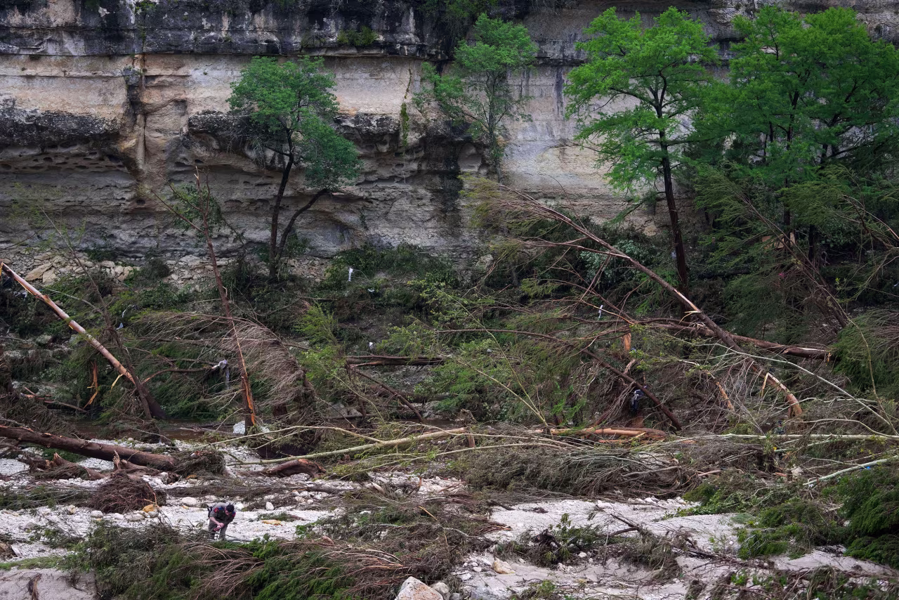 A Texas Department of Public Safety official combs through the banks of the Guadalupe River near Camp Mystic on Saturday in Hunt, Texas.
