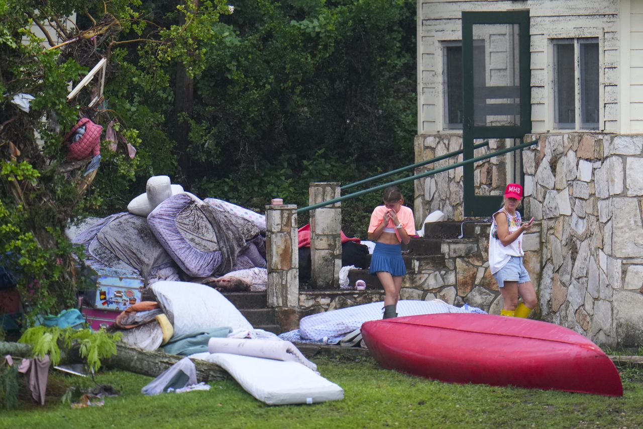 People look at belongings outside sleeping quarters at Camp Mystic in Hunt, Texas on Sunday.