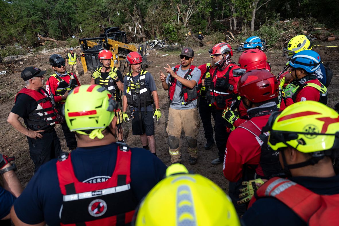 Firefighters from Ciudad Acuña, Mexico, gather for a briefing as they aid in search-and-rescue efforts in Ingram on Monday.