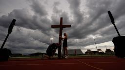 Dan Beazley, of Michigan, left, reacts as he holds a large cross with Abigail Smithson during a vigil for flooding victims at Tivy Antler Stadium on Wednesday in Kerrville, Texas. (AP Photo/Gerald Herbert)