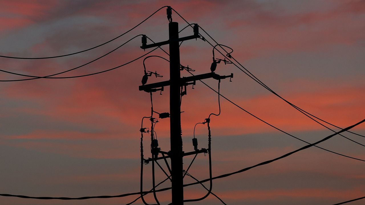 The sun rises behind power cables and telephone lines hang from a utility pole in Houston, Texas, on July 1.