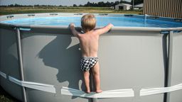 A child uses the compression strap to stand on above-ground pool.