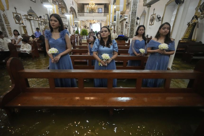 Bridemaids attend a wedding ceremony at the flooded Barasoain church in Malolos, Bulacan province, Philippines on Tuesday, July 22, 2025.