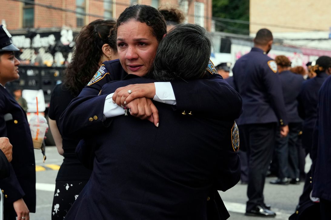 New York Police officers embrace outside Parkchester Jame Masjid.
