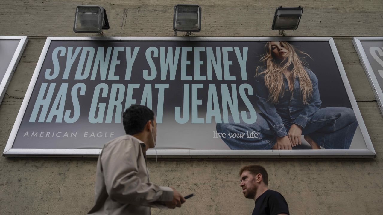 People walk past a campaign poster starring Sydney Sweeney which is displayed at the American Eagle Outfitters store, Friday, Aug. 1, 2025, in New York. (AP Photo/Yuki Iwamura)