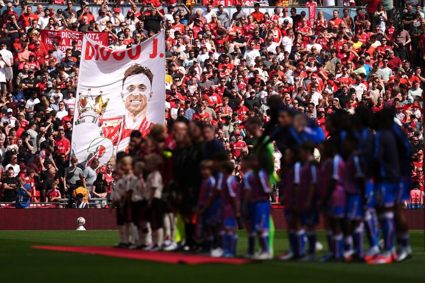 Liverpool and Crystal Palace players line up ahead of kick off as fans display a banner in memory of Liverpool's Diogo Jota.