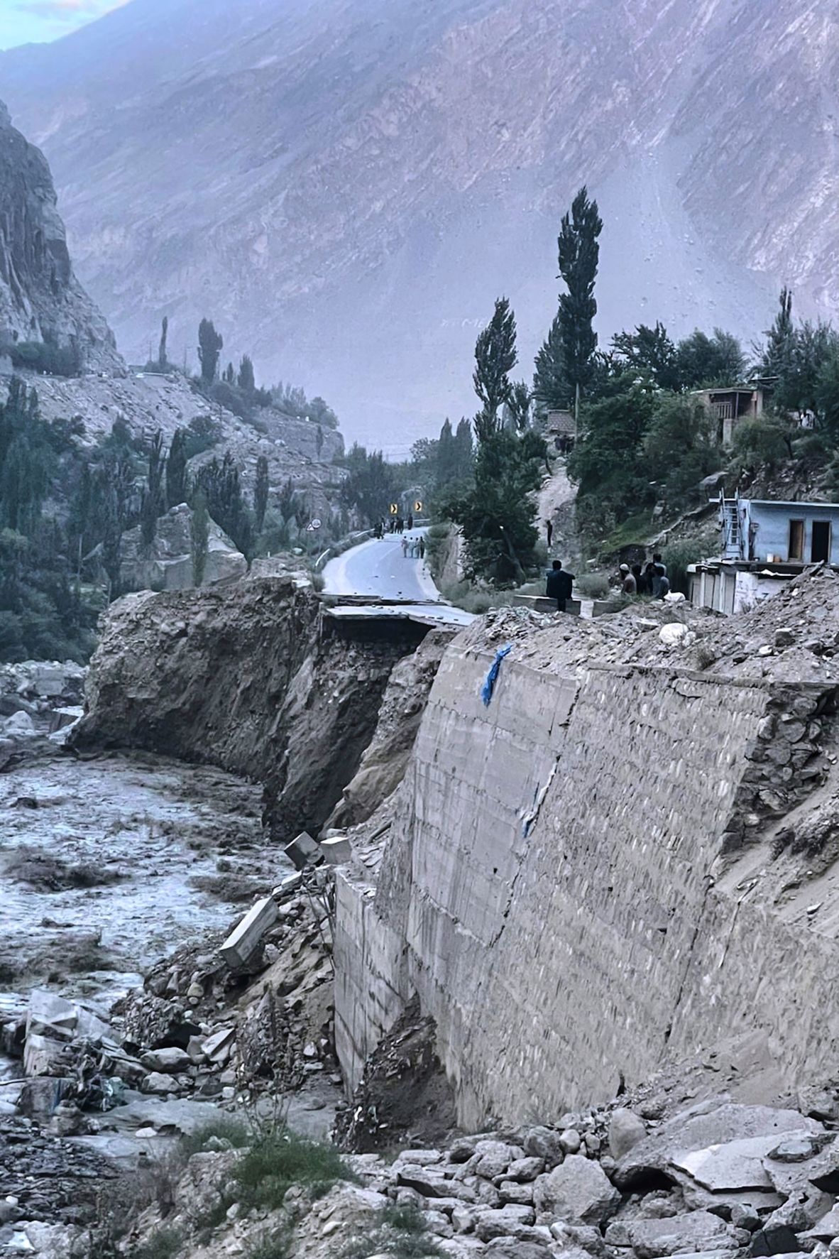 Local residents look a damaged portion of Karakoram Highway following a flash flood triggered by a glacial lake outburst near Gilgit, Pakistan, on August 10.