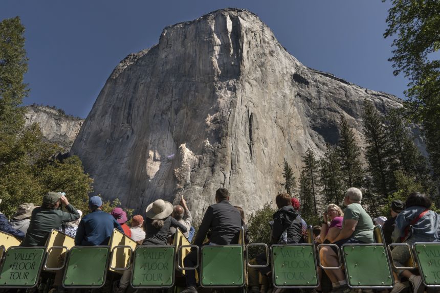 Yosemite National Park visitors view El Capitan as a transgender flag hangs from it in May.