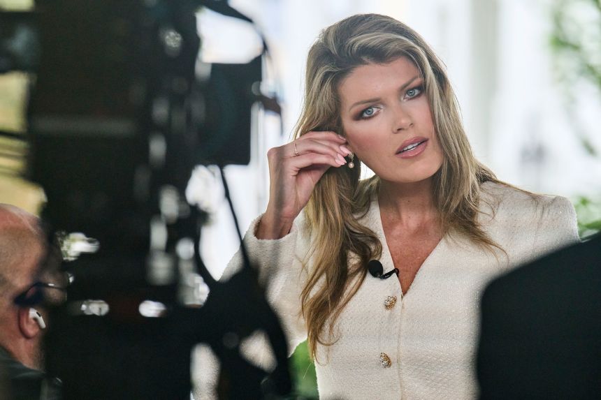 Lindsey Halligan fixes an earring at the end of an interview outside of the White House, on August 20.