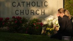 Ann Stovner kneels by a makeshift memorial at Annunciation Catholic Church after Wednesday's school shooting, Thursday, Aug. 28, 2025, in Minneapolis.