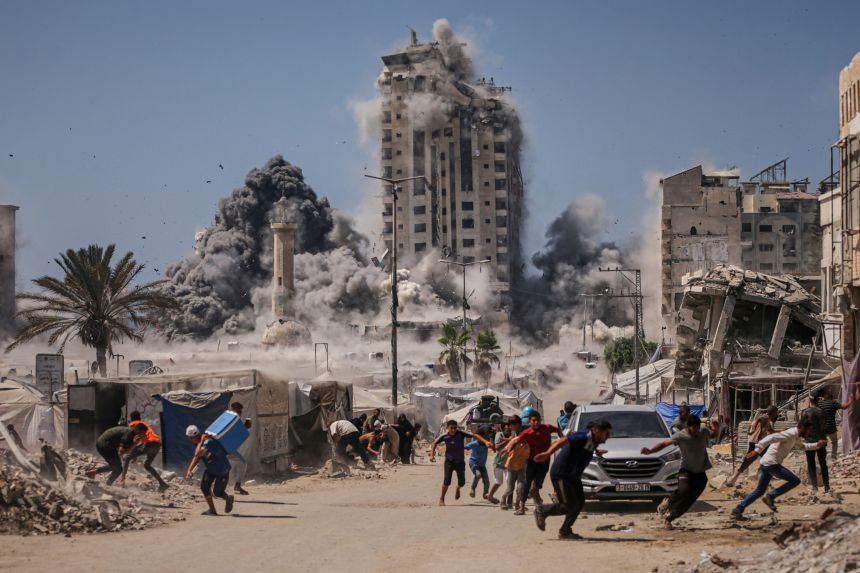 Palestinians run for cover during an Israeli airstrike on a high-rise building in Gaza City on September 5, 2025.