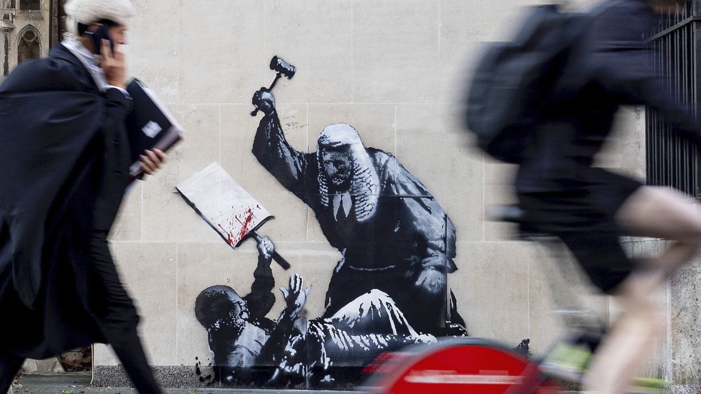 A photo released by Banksy shows the street artist's latest creation — an image of a judge beating a protester with a gavel at the Royal Courts of Justice in London.