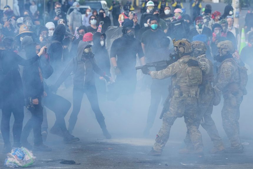 Federal officers face demonstrators as tear gas fills the air outside the Immigration and Customs Enforcement facility in Portland during a June 14 protest.